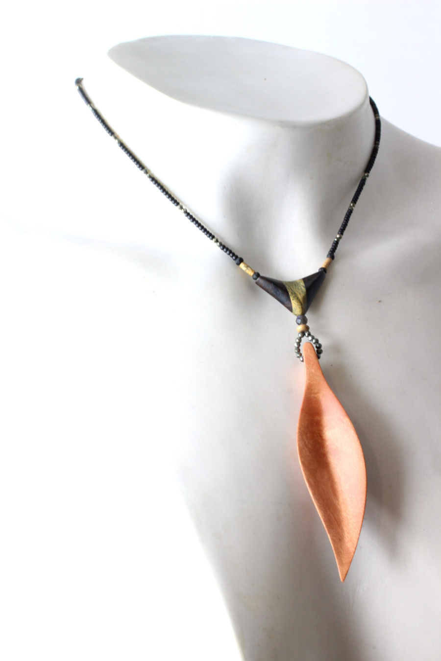 Choker en cuivre avec pendentif feuille et cordon noir texturé, élégance moderne inspirée de la nature.