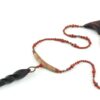 Choker design en bois exotiques & Jaspe rouge, avec pour pendentif une vrille en bois d'ébène noir, attachée par un cercle de petite perle de pyrité bronze doré scintillant, reliée à une pièce balancelle courbée en bois d'olivier crème foncé boisé, et un fil de perles rouge brique ponctués de deux de pyrite partent des deux côté de la pièce jusqu'au fermoir puzzle aimanté de forme triangulaire, avec un pendant de perles noires en fermeture