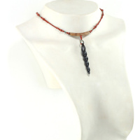 Design-Choker aus exotischen Hölzern und rotem Jaspis, mit einer Ranke aus schwarzem Ebenholz als Anhänger, die mit einem Kreis aus kleinen, glitzernden, goldbronzenen Pyritperlen befestigt ist, verbunden mit einem gebogenen Schaukelstück aus dunkel cremefarbenem, holzigem Olivenholz, und einer Perlenschnur aus ziegelroten, mit zwei Pyritperlen punktierten Perlen, die von beiden Seiten des Stücks zu einem dreieckigen, magnetischen Puzzle-Verschluss mit einem Anhänger aus schwarzen Perlen als Verschluss führt.