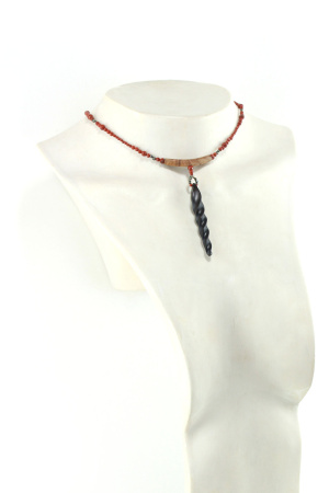 Choker design en bois exotiques & Jaspe rouge, avec pour pendentif une vrille en bois d'ébène noir, attachée par un cercle de petite perle de pyrité bronze doré scintillant, reliée à une pièce balancelle courbée en bois d'olivier crème foncé boisé, et un fil de perles rouge brique ponctués de deux de pyrite partent des deux côté de la pièce jusqu'au fermoir puzzle aimanté de forme triangulaire, avec un pendant de perles noires en fermeture