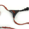 Choker design en bois exotiques & Jaspe rouge, avec pour pendentif une vrille en bois d'ébène noir, attachée par un cercle de petite perle de pyrité bronze doré scintillant, reliée à une pièce balancelle courbée en bois d'olivier crème foncé boisé, et un fil de perles rouge brique ponctués de deux de pyrite partent des deux côté de la pièce jusqu'au fermoir puzzle aimanté de forme triangulaire, avec un pendant de perles noires en fermeture