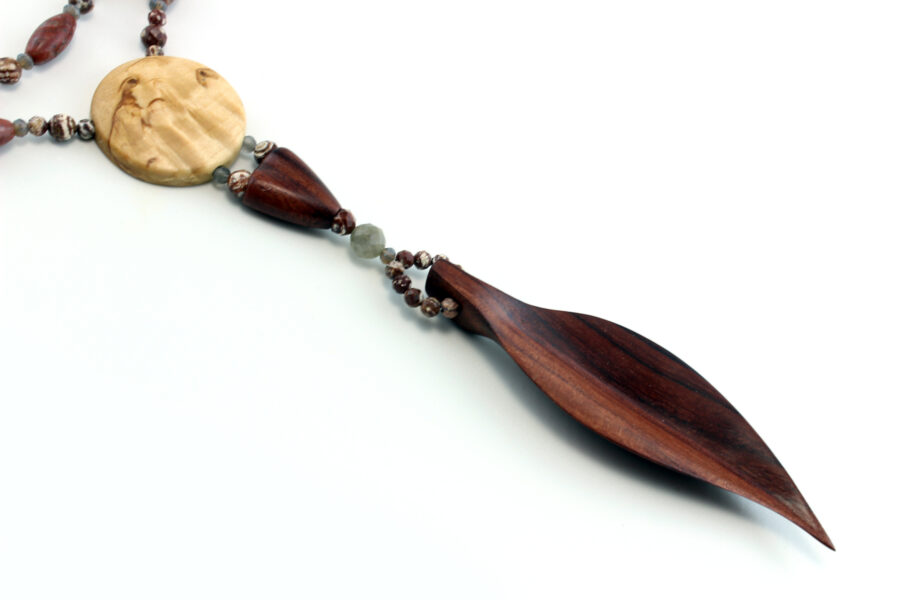 Collier Princesse en bois de Violette sculpté, avec pour pendentif une feuille élancée en bois violet foncé, un disque crème boisé, un collier de perles violet foncé avec des touches de gris et un fermoir puzzle aimanté qui se termine par un double pendant de perles