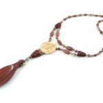 Collier Princesse en bois de Violette sculpté, avec pour pendentif une feuille élancée en bois violet foncé, un disque crème boisé, un collier de perles violet foncé avec des touches de gris et un fermoir puzzle aimanté qui se termine par un double pendant de perles