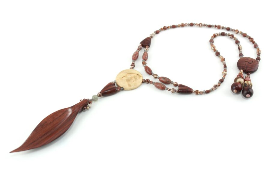 Collier Princesse en bois de Violette sculpté, avec pour pendentif une feuille élancée en bois violet foncé, un disque crème boisé, un collier de perles violet foncé avec des touches de gris et un fermoir puzzle aimanté qui se termine par un double pendant de perles