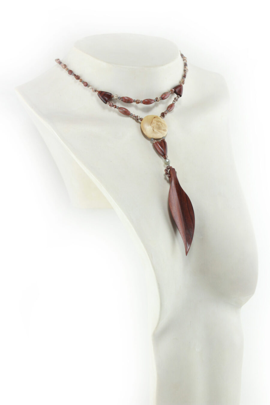 Collier Princesse en bois de Violette sculpté, avec pour pendentif une feuille élancée en bois violet foncé, un disque crème boisé, un collier de perles violet foncé avec des touches de gris et un fermoir puzzle aimanté qui se termine par un double pendant de perles