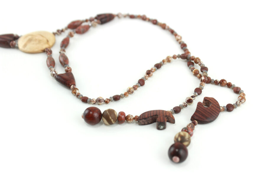 Collier Princesse en bois de Violette sculpté, avec pour pendentif une feuille élancée en bois violet foncé, un disque crème boisé, un collier de perles violet foncé avec des touches de gris et un fermoir puzzle aimanté qui se termine par un double pendant de perles