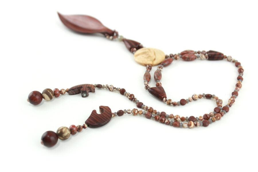 Collier Princesse en bois de Violette sculpté, avec pour pendentif une feuille élancée en bois violet foncé, un disque crème boisé, un collier de perles violet foncé avec des touches de gris et un fermoir puzzle aimanté qui se termine par un double pendant de perles