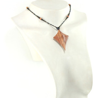 Collar de madera en forma de cruz primitiva: collar de cuentas metálicas negras, naranjas y verdes sujetas con un cierre magnético. Colgante en forma de cruz curvada hacia arriba, con líneas que forman una cruz sinuosa.