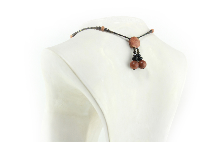 Collier croix primitive en bois : collier de perles noires, orange et vert métallisé fermé par un fermoir aimanté.