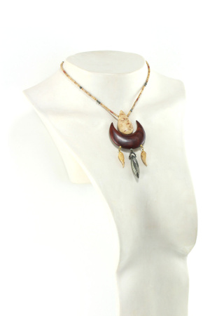 Collier demi-lune en bois de Cocobolo sculpté, avec une demi lune en bois orange foncé, une fève couleur bronze en bas au milieu, deux petites feuilles crème boisé, sur chaque côté. sur le dessus, à l'intérieur de la demi lune, une fève crème boisé d'où partent deux fils de perles crème boisé jusqu'au fermoir puzzle aimanté en bois orange et crème boisé