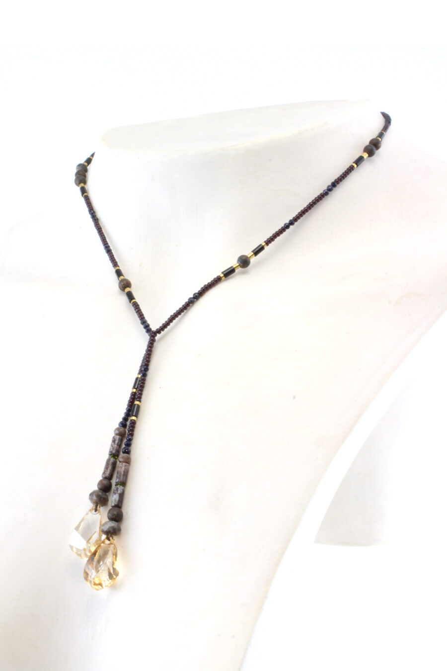 un collier lariat sensuel en perles naturelles de Bronzite et perles noires avec des touches dorées et marron qui se termine par deux cristaux de couleur ambre