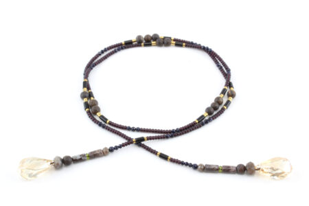 un collier lariat sensuel en perles naturelles de Bronzite et perles noires avec des touches dorées et marron qui se termine par deux cristaux de couleur ambre