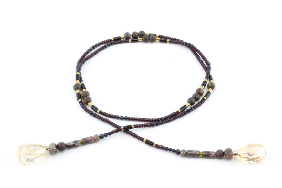 un collier lariat sensuel en perles naturelles de Bronzite et perles noires avec des touches dorées et marron qui se termine par deux cristaux de couleur ambre