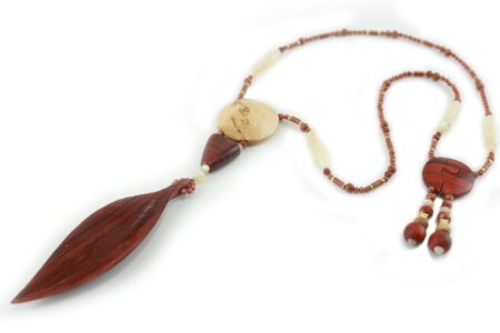 Princesse Padouk à Calcite, avec pour pendentif une feuille élancée en bois orange foncé, un disque crème boisé, un collier de perles orange foncé avec des touches de crème et un fermoir puzzle aimanté qui se termine par un double pendant de perles