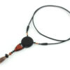Collier totem en bois exotiques et Jaspe Picasso, avec en pendentif un disque noir ébène, une petite pièce en bois bombée orange foncé, une suite de perles et une pierre sculptée en forme d'olive vert tacheté d'orange. Cordon de cuir noir relié aux pendant avec deux pièces de bois sculpté en forme d'olive