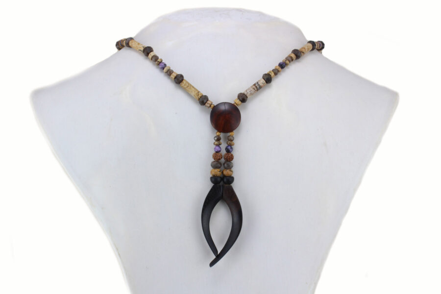 Collier choker en bois précieux et perles naturelles , dont la forme rappelle une pince noire en ébène qui tient en son centre une pleine lune en cocobolo