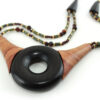 Ras-de-cou artisanal en bois naturel d'Ebène, avec un cercle donuts noir, deux pièces en bois orange qui l'encadrent vers le haut du cercle, deux ranges de perles les prolongent jusqu'à deux pièces en bois intermédiaires qui font le lien avec le fermoir puzzle aimanté noir