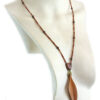 Sautoir-en-Bois-exotique-perles-naturelles avec une feuille élancée jaune en pendant, reliée à un cercle de perles vertes et une petite pièce en bois bombée d'où part la partie suite de perle. Collier sautoir long, la feuille arrive au creux de la poitrine