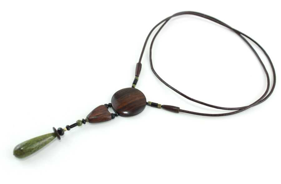 Sautoir en bois sculpté & perles naturelles : cordon en cuir avec pendant ethnique, un cercle sculpté en bois marron relié par des perles noires à une pièce en bois bombée marron, reliée à une suite de perles qui se terminent par une pierre verte d'Unakite