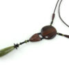 Sautoir en bois sculpté & perles naturelles : cordon en cuir avec pendant ethnique, un cercle sculpté en bois marron relié par des perles noires à une pièce en bois bombée marron, reliée à une suite de perles qui se terminent par une pierre verte d'Unakite