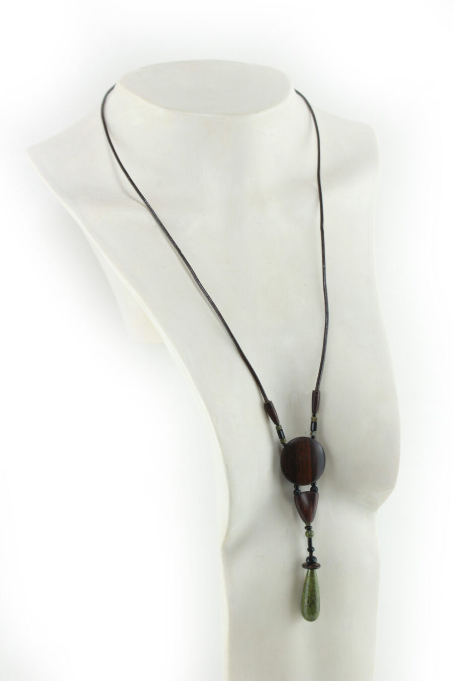 Sautoir en bois sculpté & perles naturelles : cordon en cuir avec pendant ethnique, un cercle sculpté en bois marron relié par des perles noires à une pièce en bois bombée marron, reliée à une suite de perles qui se terminent par une pierre verte d'Unakite