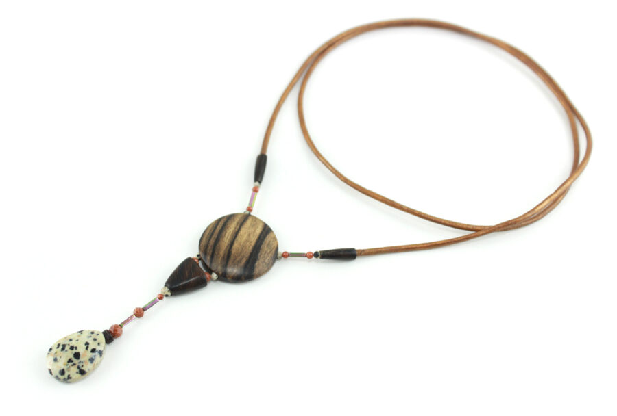 Sautoir magnétique en Ziricote & Jaspe dalmatien, avec un cordon de cuir orange relié à deux pièces de fermeture de bous marron, un cercle relié à une pièce en bois bombée puis une goutte de pierre blanche tachetée de noir