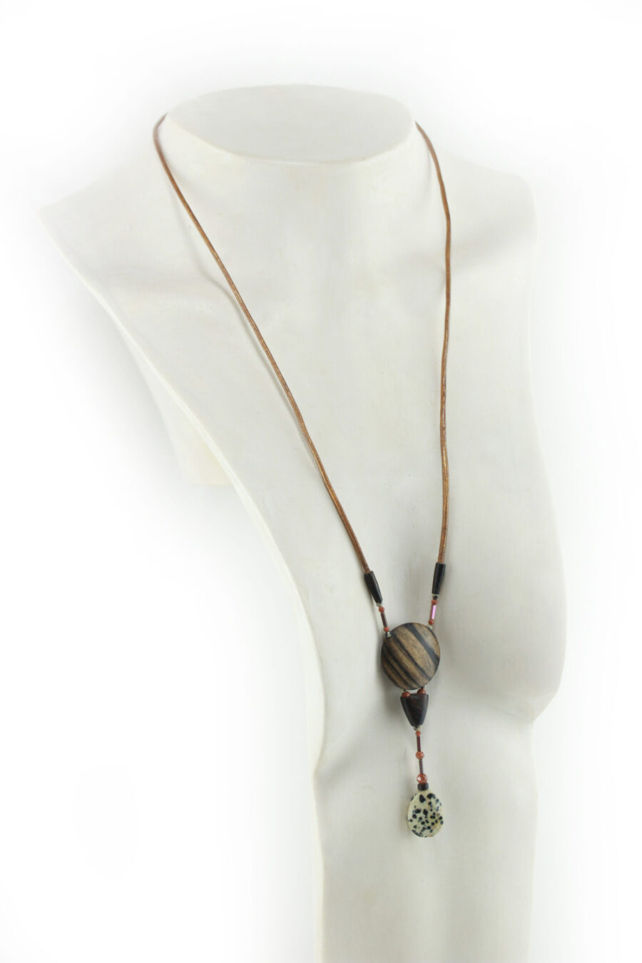 Sautoir magnétique en Ziricote & Jaspe dalmatien, avec un cordon de cuir orange relié à deux pièces de fermeture de bous marron, un cercle relié à une pièce en bois bombée puis une goutte de pierre blanche tachetée de noir